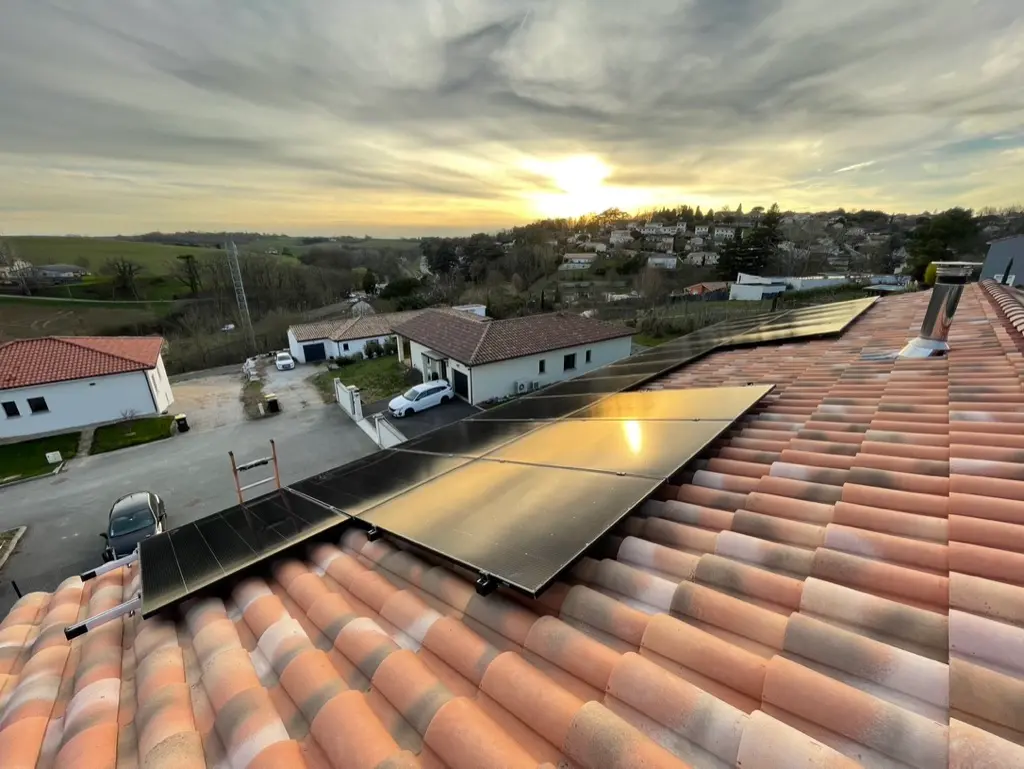 Coucher de soleil sur 21 panneaux solaires posés sur la toiture en tuile d'une maison à Montastruc